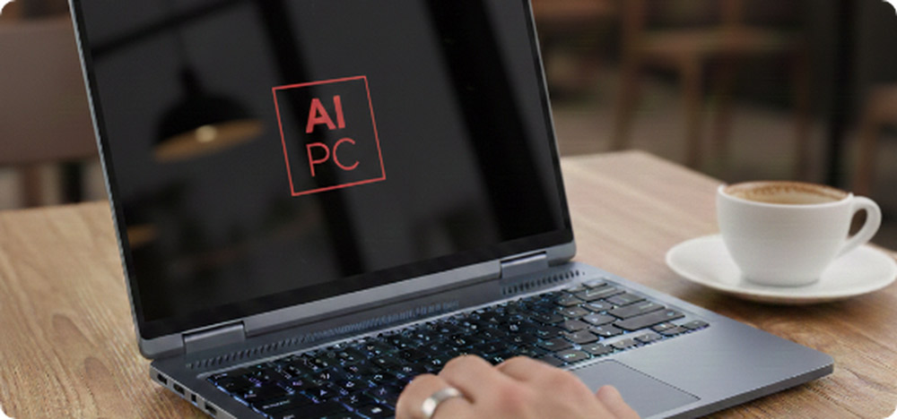 Primer plano de un notebook de última generación mostrando el logotipo 'AI PC' en la pantalla, destacando la integración de inteligencia artificial, situado sobre una mesa de madera.