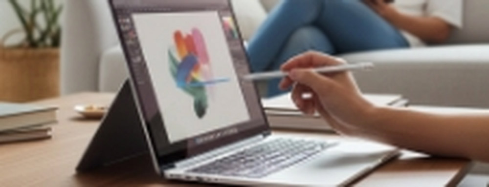 Persona utilizando un lápiz óptico para diseñar en la pantalla táctil de un notebook 2 en 1 colocado en modo atril sobre una mesa de centro en una sala de estar.