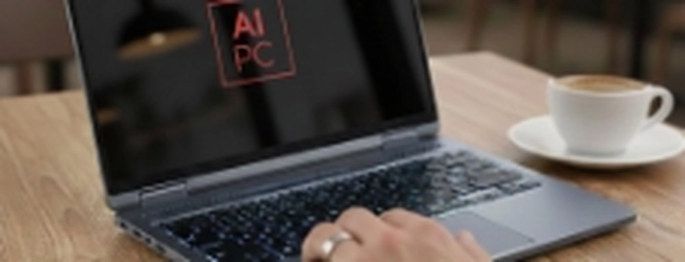 Primer plano de un notebook de última generación mostrando el logotipo 'AI PC' en la pantalla, destacando la integración de inteligencia artificial, situado sobre una mesa de madera.