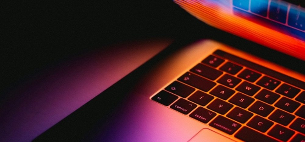 Primer plano artístico y detallado de un teclado de notebook iluminado con tonos cálidos de color naranja y púrpura, simbolizando la diversidad de categorías y diseños.