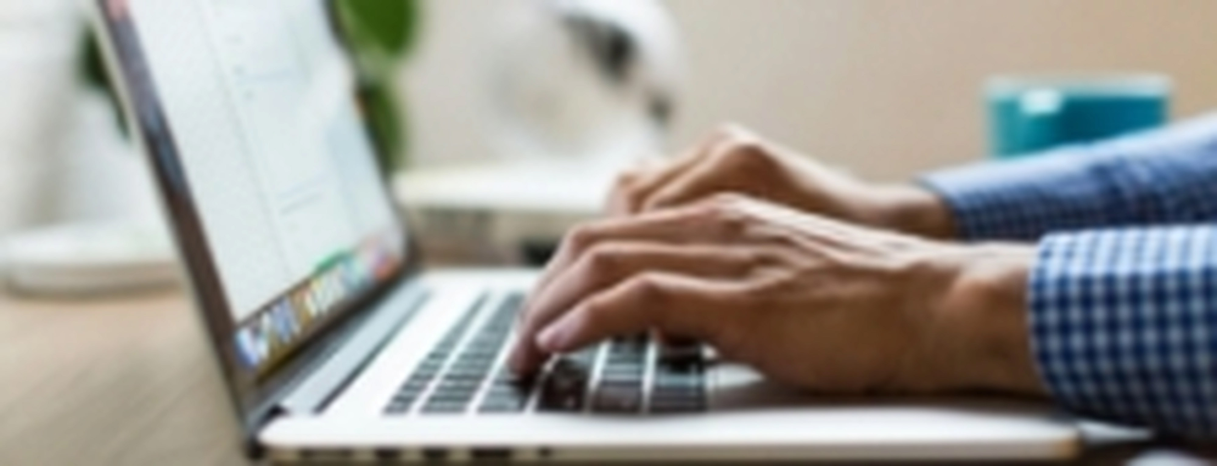Ultrabook de diseño delgado y moderno abierto sobre un escritorio minimalista. Una mano navega por el trackpad mientras la pantalla muestra una interfaz de escritorio con ventanas flotantes.