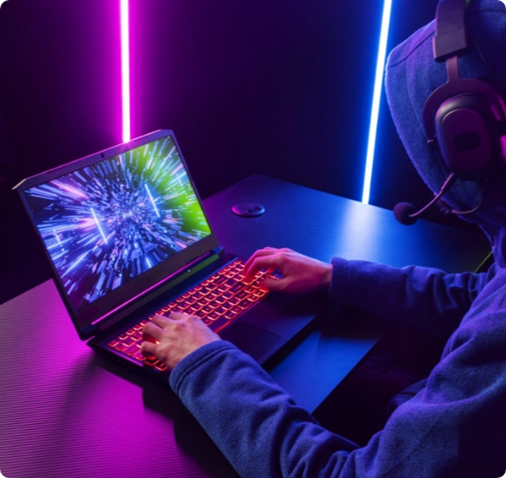 Jugador con auriculares usando un notebook gamer potente con teclado retroiluminado en rojo; la pantalla muestra un efecto de túnel de luz azul y neón en un ambiente oscuro.