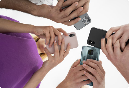 Grupo de personas en círculo comparando y usando diferentes marcas y modelos de smartphones, vista desde abajo.